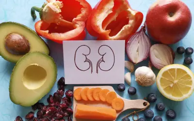 Zdrowe produkty spożywcze: awokado, papryka, jabłko, cebula, czosnek, cytryna, borówki, żurawina i marchewka. Ilustracja nerek sugeruje kłębuszkowe zapalenie nerek dieta.