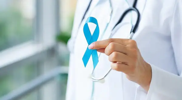 Lekarz trzyma niebieską wstążkę, symbol walki z rakiem prostaty. Badanie rezonansem magnetycznym prostaty jest kluczowe w diagnostyce.